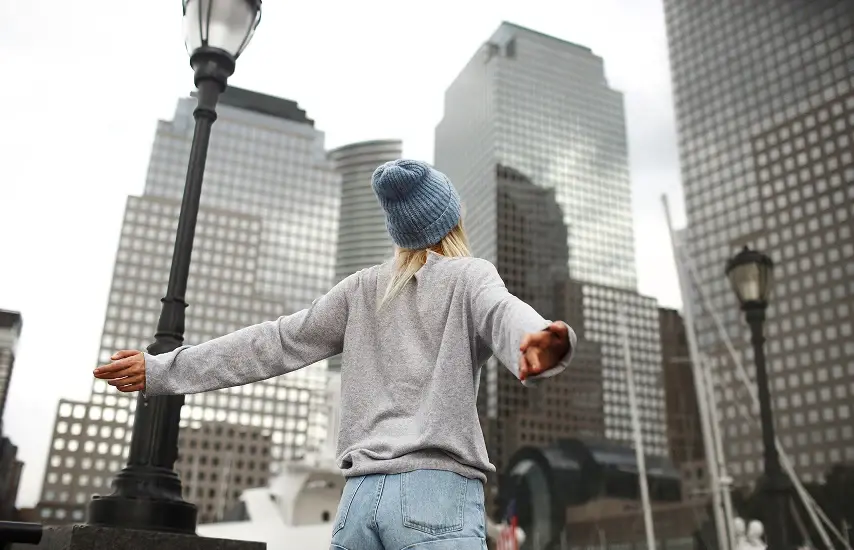 Femme avec les bras tendus devant les gratte-ciel de New York